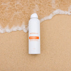 Spray After Sun doTERRA 170g — frasco em areia húmida com espuma de onda, vista zenital, aromaterapia