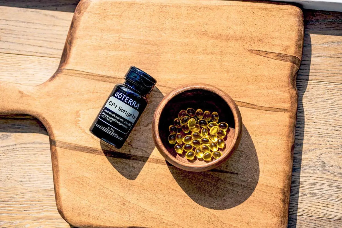 Cápsulas Moles CP+ doTERRA — tábua de madeira com tigela e cápsulas douradas, suplemento natural