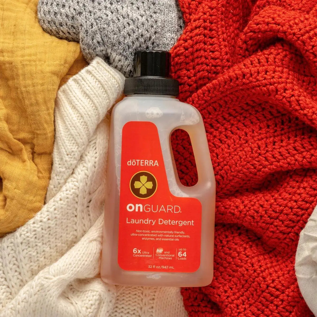 Detergente de Roupa On Guard doTERRA 947ml — peças de roupa coloridas vista de cima, limpeza natural concentrada