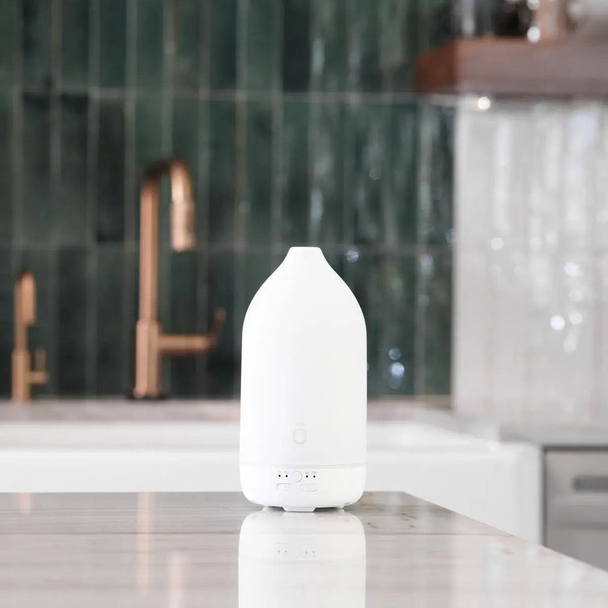 Difusor Laluz doTERRA branco — cozinha com mármore torneira cobre e azulejos verdes, aromaterapia