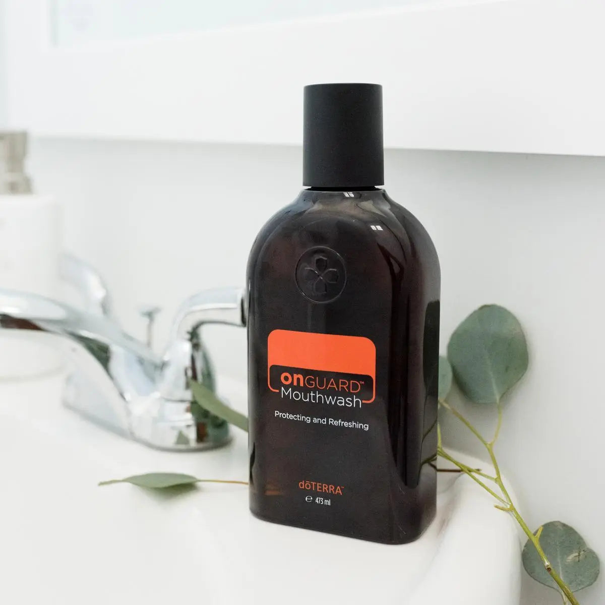 Elixir Oral On Guard doTERRA 473ml — frasco sobre bancada de banho com folhas de eucalipto, aromaterapia, óleo essencial puro CPTG