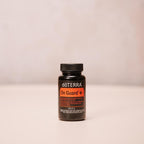 On Guard+ Softgels doTERRA — frasco de cápsulas moles centrado em fundo neutro com textura, suplemento natural
