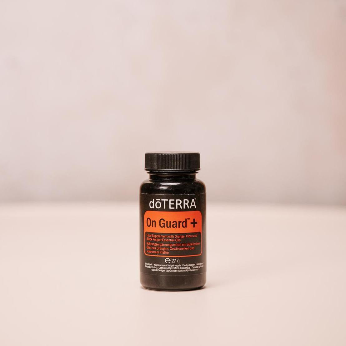 On Guard+ Softgels doTERRA — frasco de cápsulas moles centrado em fundo neutro com textura, suplemento natural