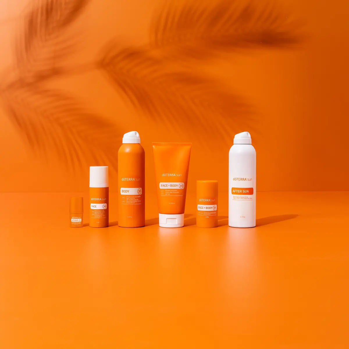 Protetor Solar Mineral doTERRA — gama completa em estúdio com fundo laranja e sombra de palmeira 2026
