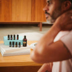 Kit Técnico AromaTOUCH doTERRA — caixa com óleos em mesa de madeira com homem ao fundo, massagem profissional