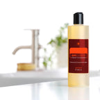 On Guard Concentrado doTERRA 355ml — frasco em estúdio com torneira e planta ao fundo, limpeza natural