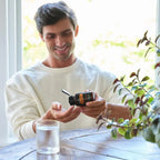 MetaPWR Mito2Max doTERRA 60 cápsulas — homem sorrindo à mesa de madeira com cápsulas, suplemento natural de energia