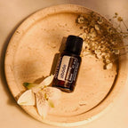 Mistura Abode doTERRA 15ml — frasco em bandeja de terracota com flores brancas e flores secas, aromaterapia purificadora