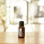 Mistura Abode doTERRA 15ml — frasco sobre mesa de madeira com bokeh interior, aromaterapia para o lar