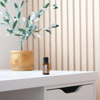 Mistura Abode doTERRA 15ml — frasco em secretária branca com vaso de madeira, difusão de aromas para escritório
