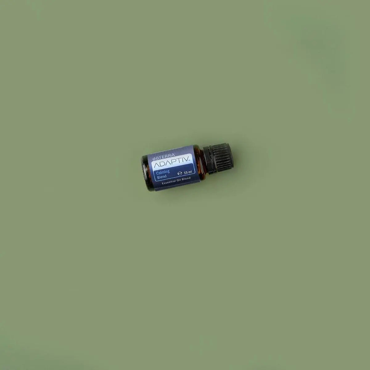 Mistura Adaptiv doTERRA 15ml — frasco inclinado em fundo verde-oliva, vista zenital, óleo essencial puro CPTG