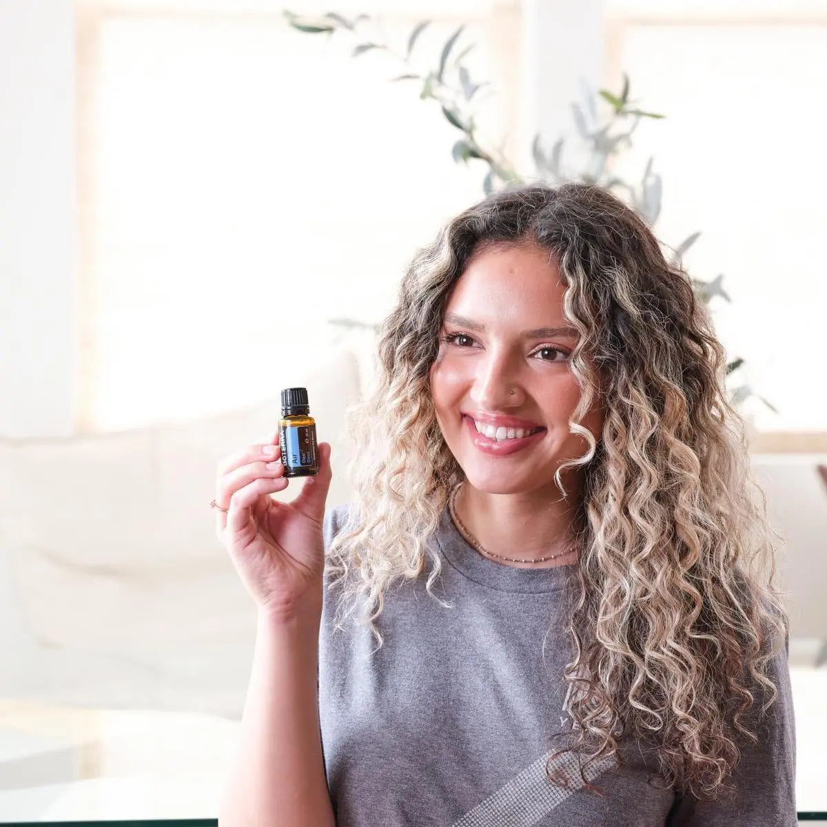 Mistura Air doTERRA 15ml — mulher loira encaracolada a segurar frasco numa sala com plantas, bem-estar respiratório