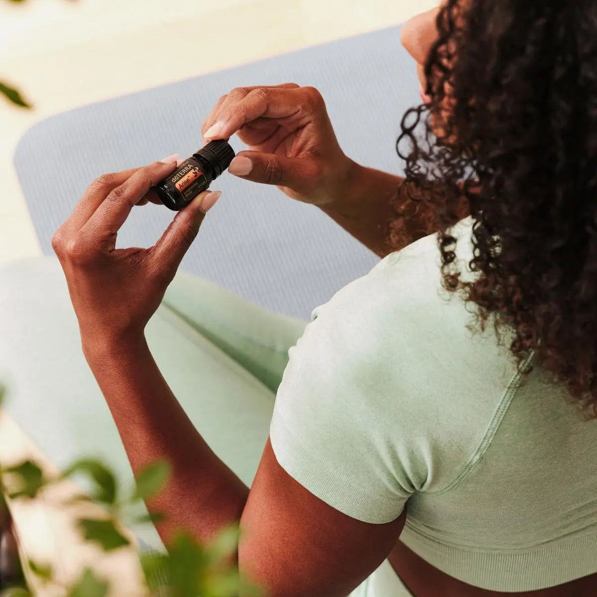 Mistura Arise doTERRA 5ml mulher segurando frasco yoga azul, elevação bem-estar óleo essencial puro