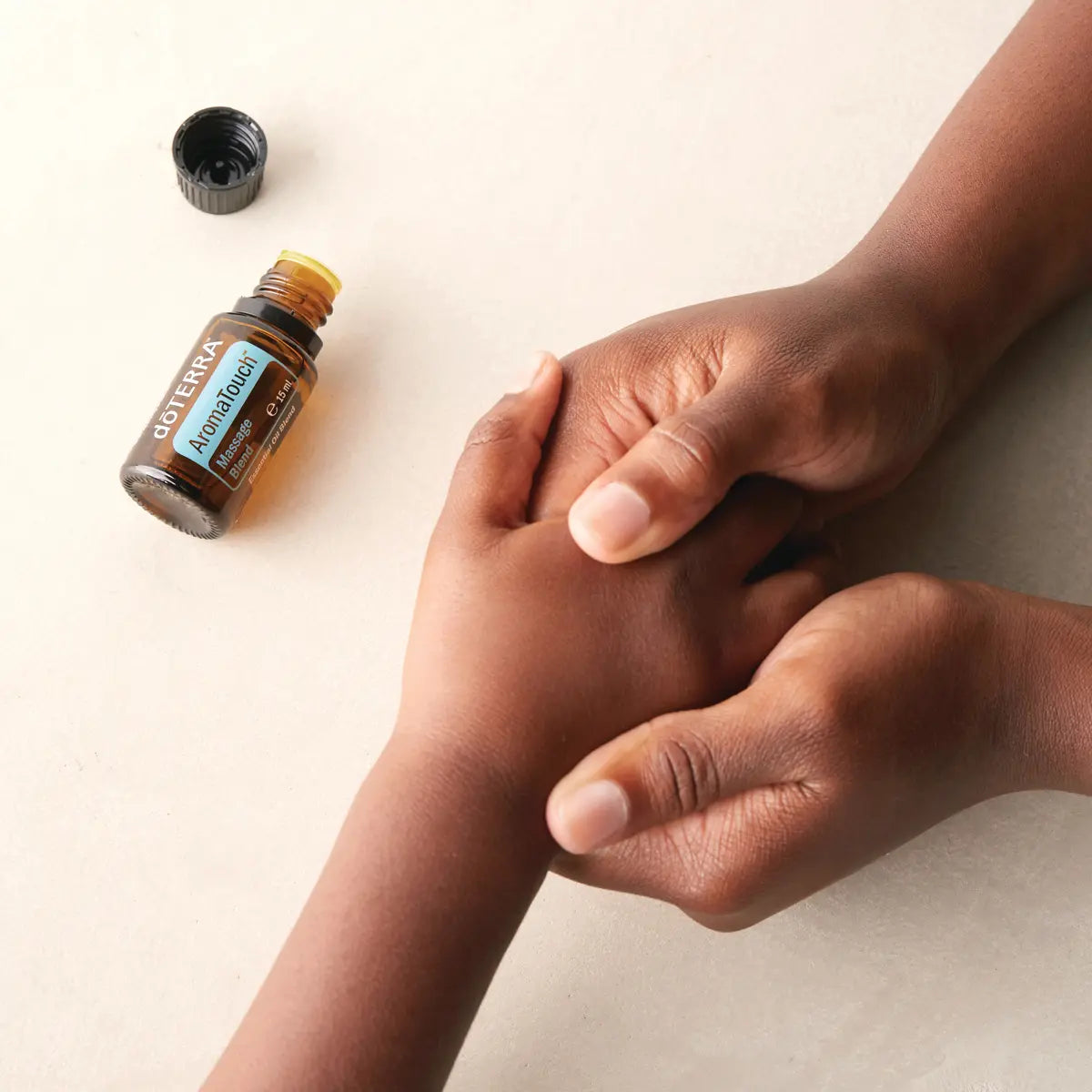 AromaTouch doTERRA 15ml mãos pele escura massagem palma fundo bege, bem-estar natural CPTG