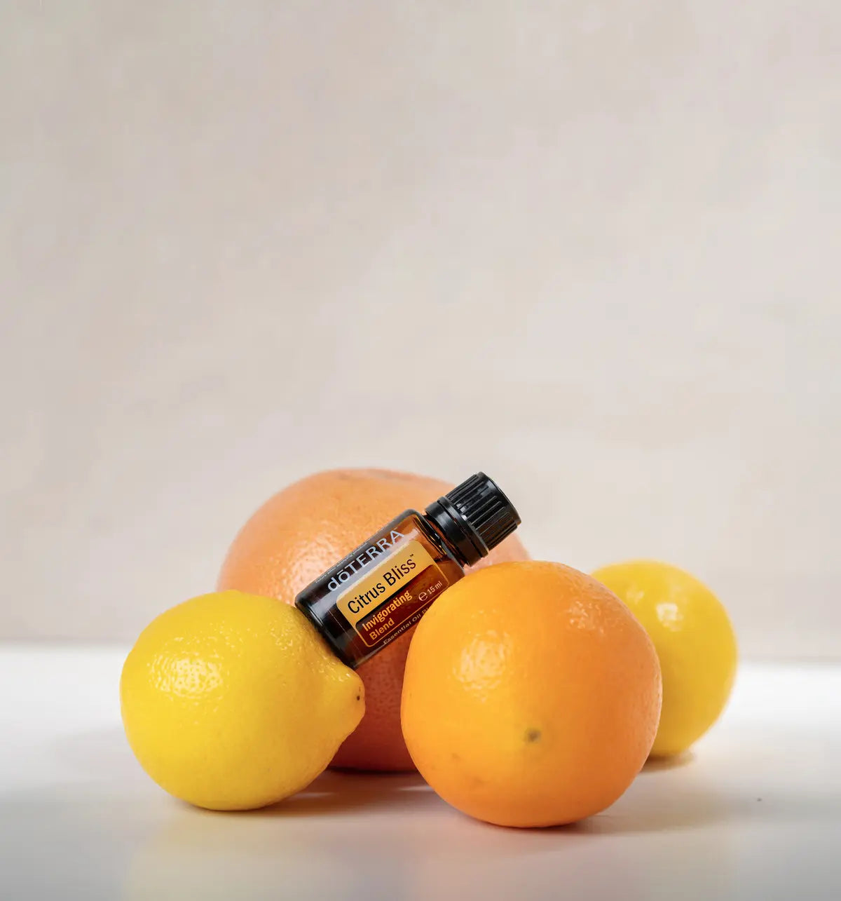 Citrus Bliss doTERRA 15ml frasco entre cítricos variados fundo bege, alegria aromaterapia CPTG