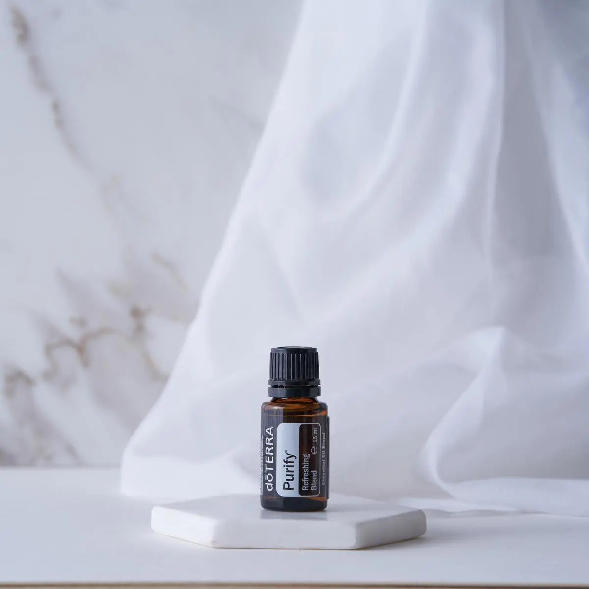 Mistura Purify doTERRA 15ml — base cerâmica hexagonal com tecido branco, fundo mármore, óleo essencial puro CPTG