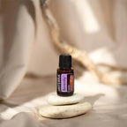 Mistura Serenity doTERRA 15ml — frasco com pedras zen empilhadas, luz quente, fundo bege, óleo essencial puro CPTG