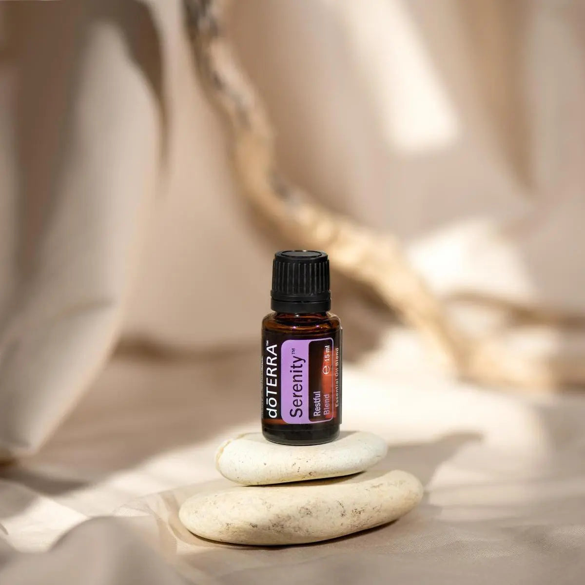 Mistura Serenity doTERRA 15ml — frasco com pedras zen empilhadas, luz quente, fundo bege, óleo essencial puro CPTG