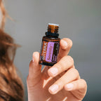 Mistura Serenity doTERRA 15ml — mão ruiva segurando frasco aberto, primeiro plano cinzento, óleo essencial relaxante