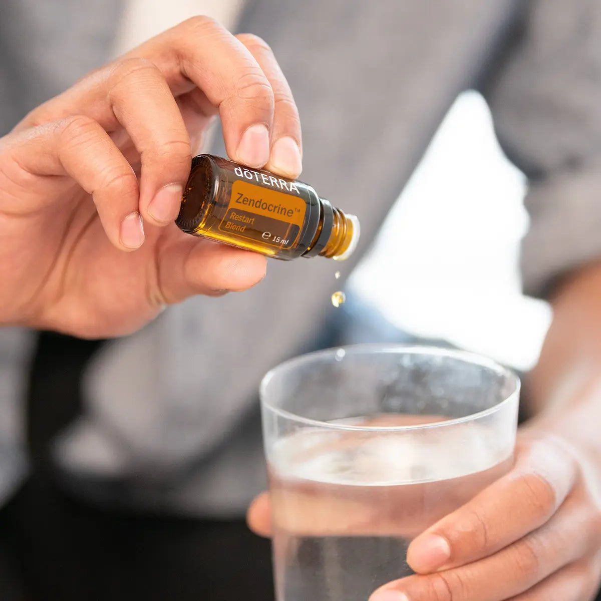 Zendocrine doTERRA 15ml — mãos colocando gota em vaso com água e gelo, primeiro plano, óleo essencial purificante