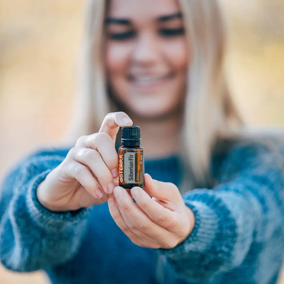 Óleo Essencial Abeto Siberiano doTERRA 15ml — mulher sorridente a usar óleo essencial puro no exterior