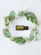 Óleo Essencial Árvore do Chá doTERRA 15ml — vista zenital com coroa de eucalipto e tecido branco, óleo essencial puro CPTG
