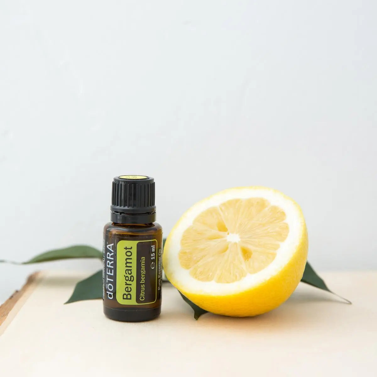Óleo Essencial Bergamota doTERRA 15ml — tábua de madeira com fruta e folhas, fundo cinzento, óleo essencial puro