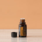 Óleo Essencial Cássia doTERRA 15ml — frasco aberto sobre mármore fundo pêssego, óleo essencial CPTG puro, aromaterapia