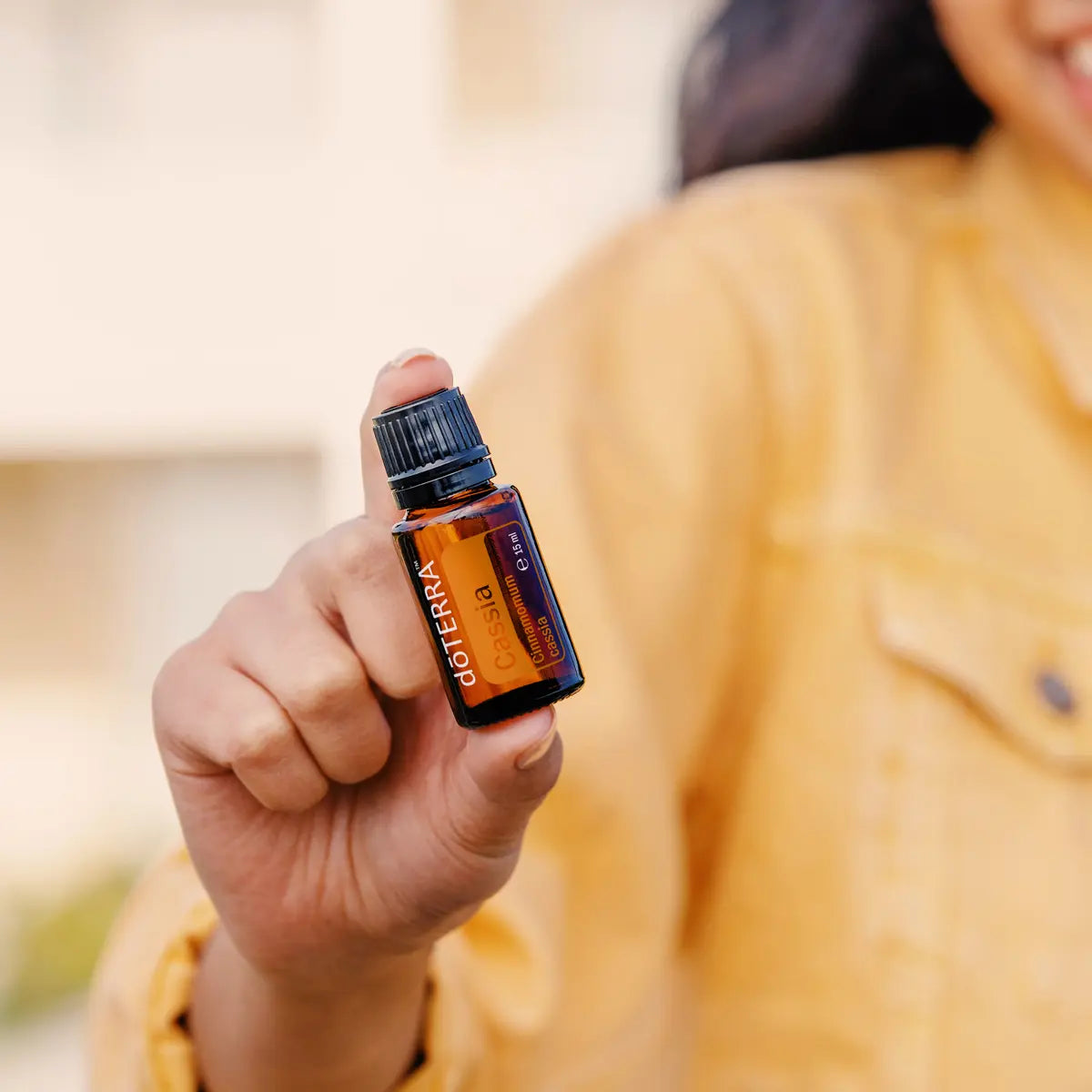 Óleo Essencial Cássia doTERRA 15ml — mulher com casaco amarelo no exterior, uso quotidiano, bem-estar natural