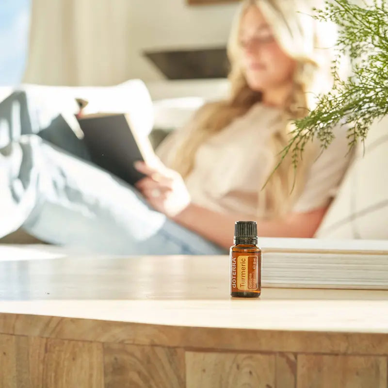 Óleo Essencial Cúrcuma doTERRA 15ml — mesa de sala com mulher a ler no sofá, aromaterapia bem-estar