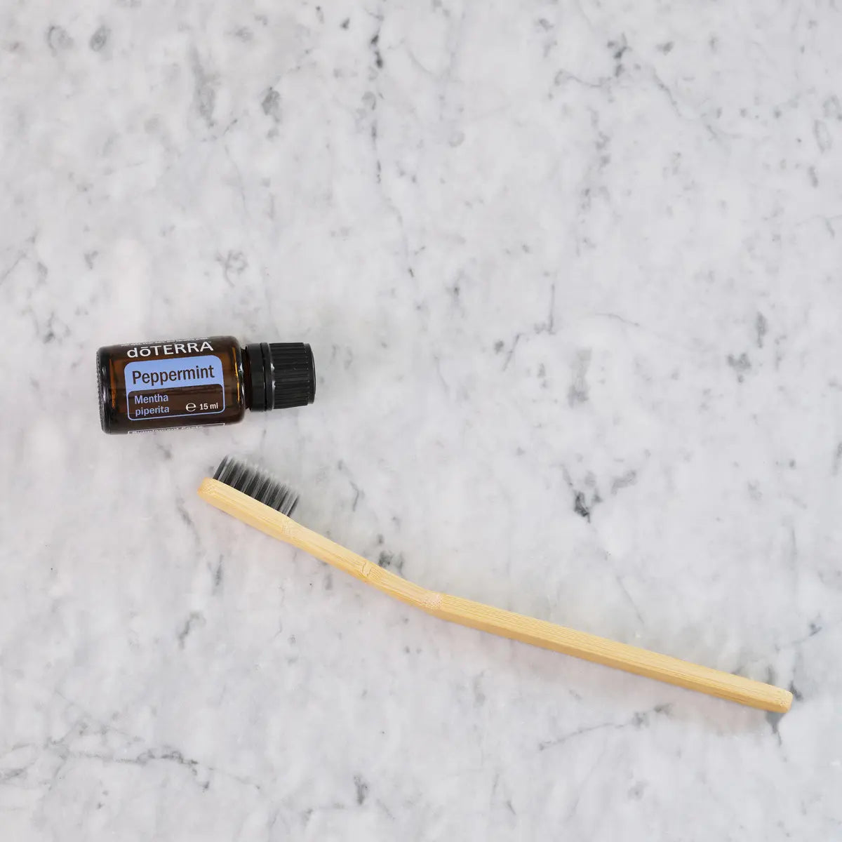 Óleo Essencial Hortelã-Pimenta doTERRA 15ml — com escova de dentes bambu sobre mármore branco, higiene natural
