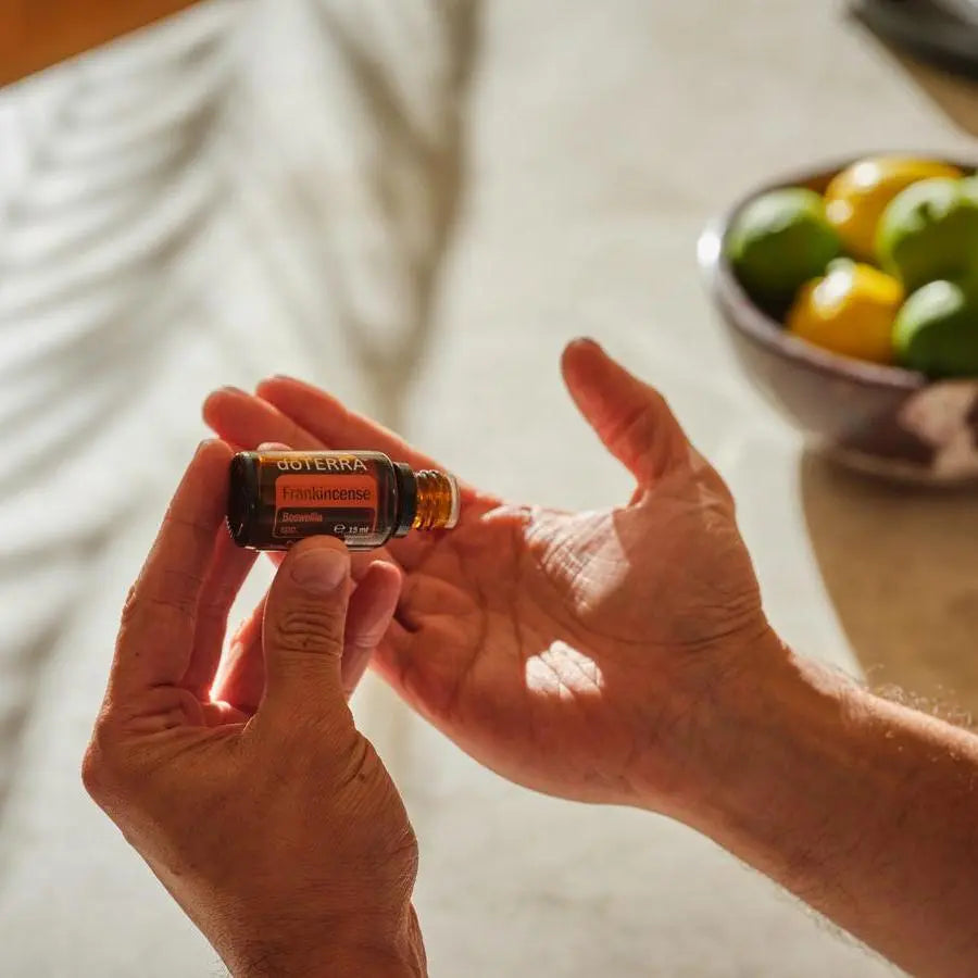 Óleo Essencial Incenso doTERRA 15ml — mãos aplicando sobre mesa com cítricos, cuidado da pele puro CPTG