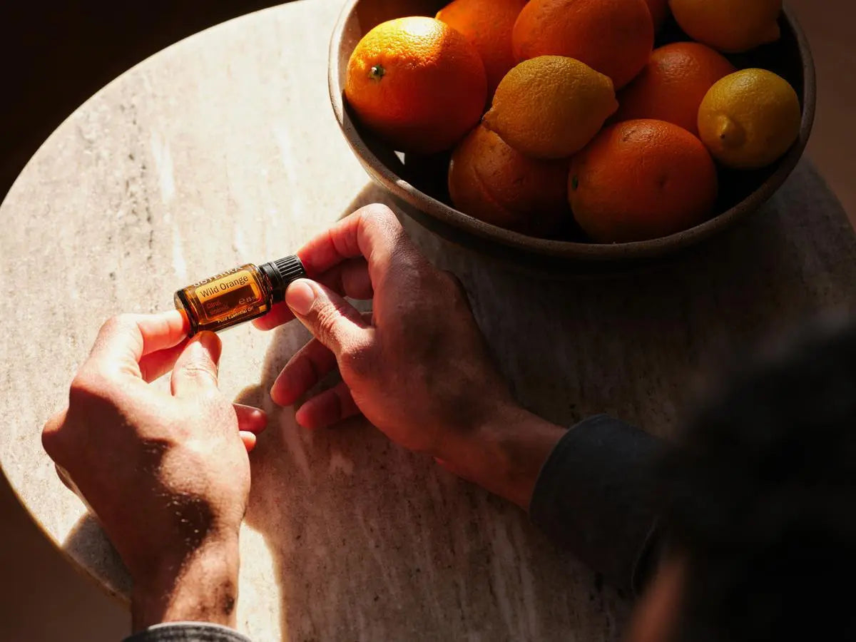 Óleo Essencial Laranja Silvestre doTERRA 15ml — sobre mesa de pedra com laranjas e limões, uso culinário CPTG