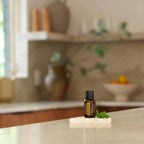 Óleo Essencial Manjerona doTERRA 15ml — frasco sobre pedra travertino com folha de manjerona em cozinha moderna, aromaterapia, óleo essencial puro CPTG
