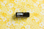 Óleo Essencial Melissa doTERRA 5ml — flat lay com frasco sobre tecido estampado floral amarelo, aromaterapia, óleo essencial puro CPTG