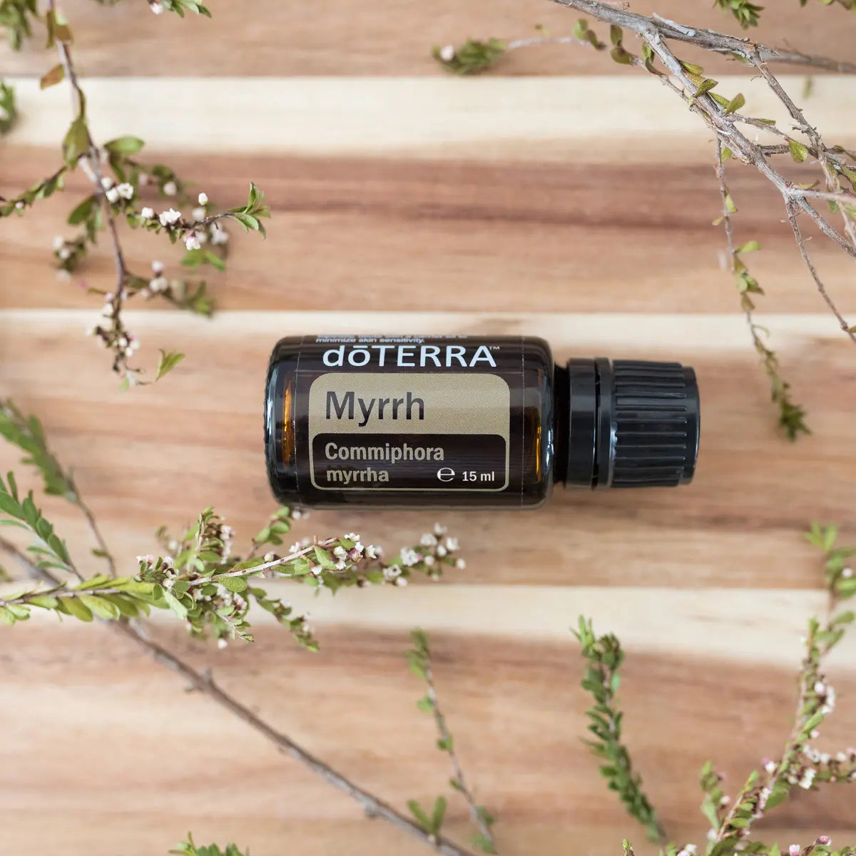 Óleo Essencial Mirra doTERRA 15ml — flat lay sobre tábua de madeira quente com ramos de flores brancas, aromaterapia, óleo essencial puro CPTG