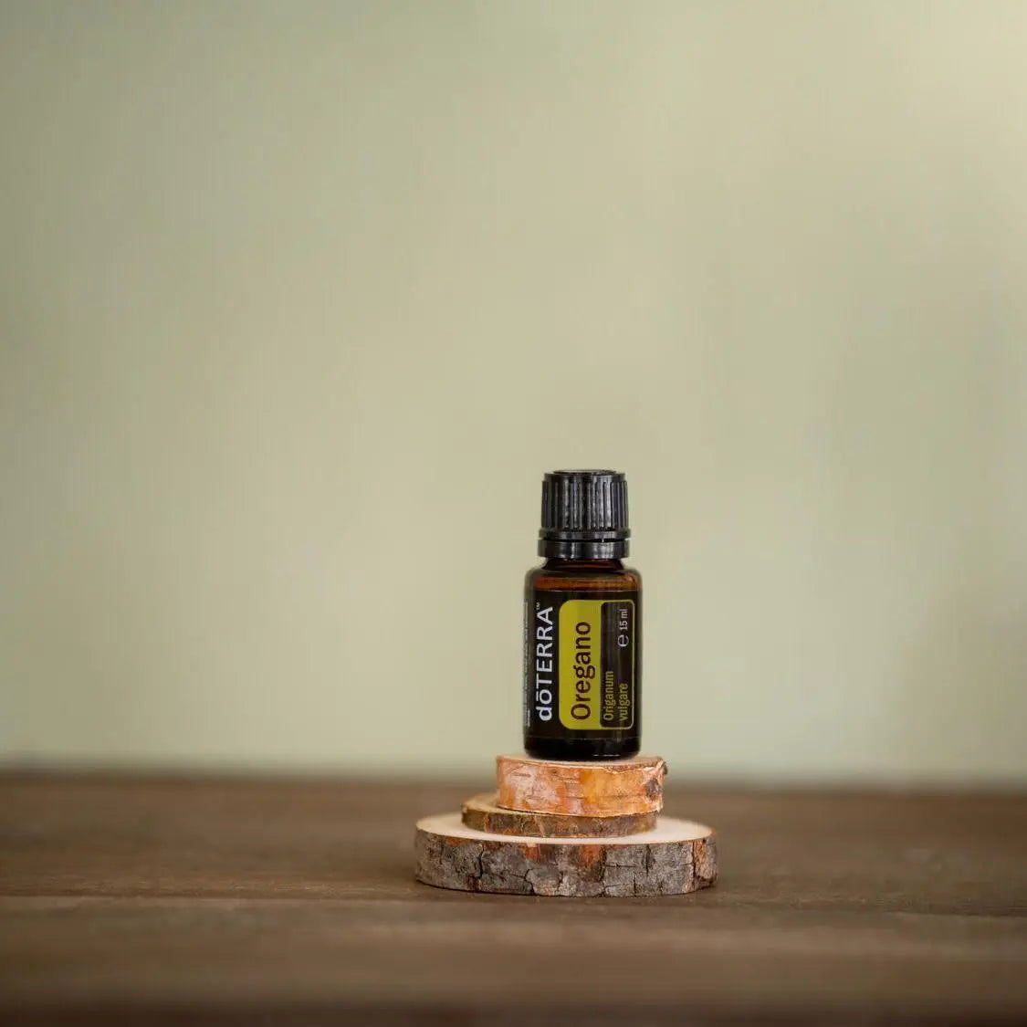 Óleo Essencial Orégão doTERRA 15ml — frasco sobre rodelas de bétula com fundo verde e salva, aromaterapia, óleo essencial puro CPTG