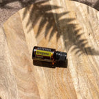 Óleo Essencial Orégão doTERRA 15ml — frasco sobre tábua de madeira com sombra de folha de palma, aromaterapia, óleo essencial puro CPTG