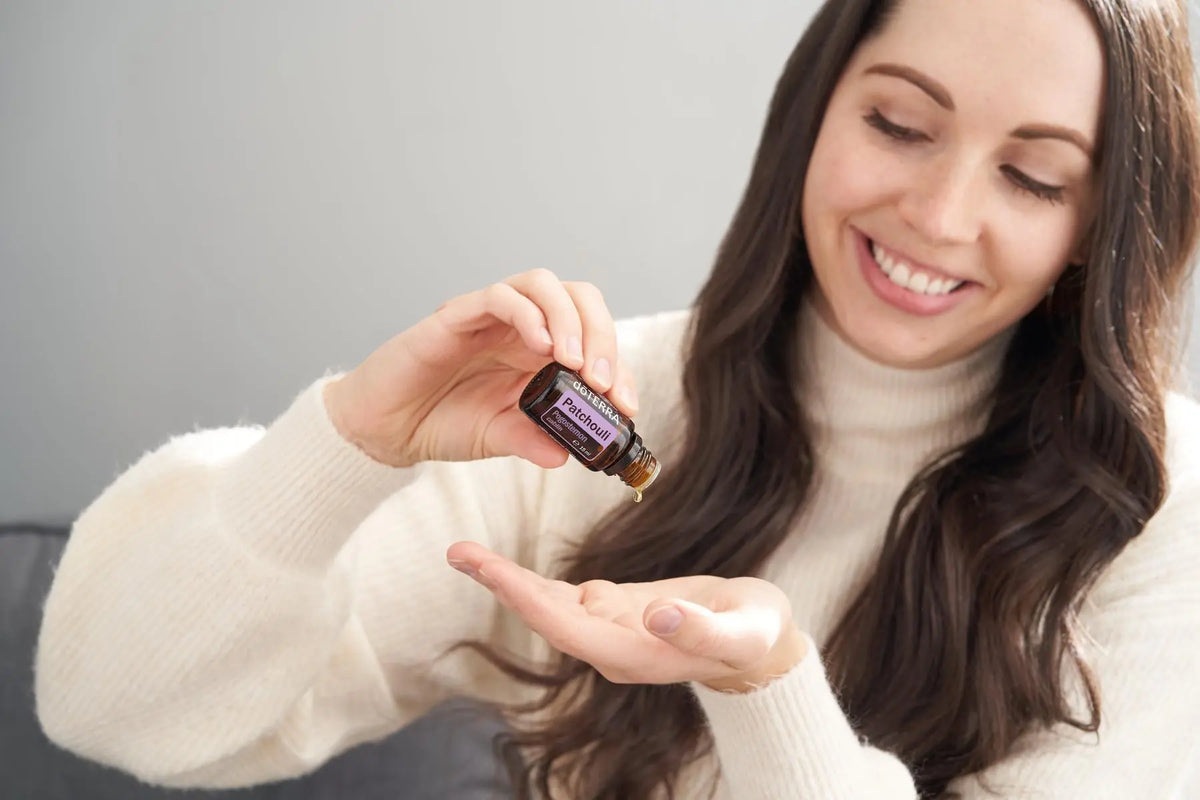 Óleo Essencial de Patchouli doTERRA 15ml mulher aplicando gota na palma — aromaterapia CPTG