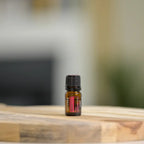 Óleo Essencial de Rosa doTERRA 5ml — frasco em tábua de madeira natural com fundo neutro desfocado, aromaterapia, óleo essencial puro CPTG