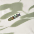 Óleo Essencial de Sálvia Esclareia doTERRA 15ml — frasco deitado em linho creme com sombras de folhas vista zenital, aromaterapia, óleo essencial puro CPTG
