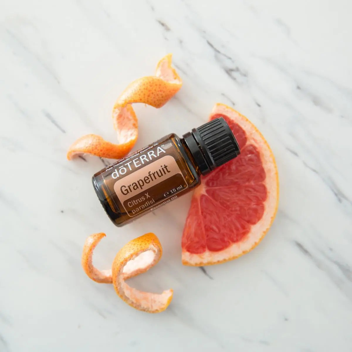 Óleo Essencial de Toranja doTERRA 15ml — mármore com rodela de toranja e espiral de pele cítrica vista zenital, aromaterapia, óleo essencial puro CPTG