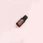Óleo Essencial de Gerânio doTERRA 15ml — frasco inclinado em fundo rosa pastel, aromaterapia, óleo essencial puro CPTG