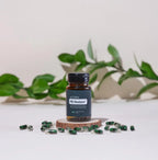 PB Restore doTERRA — frasco em rodela de madeira com cápsulas verdes e folhas, estúdio, suplemento CPTG
