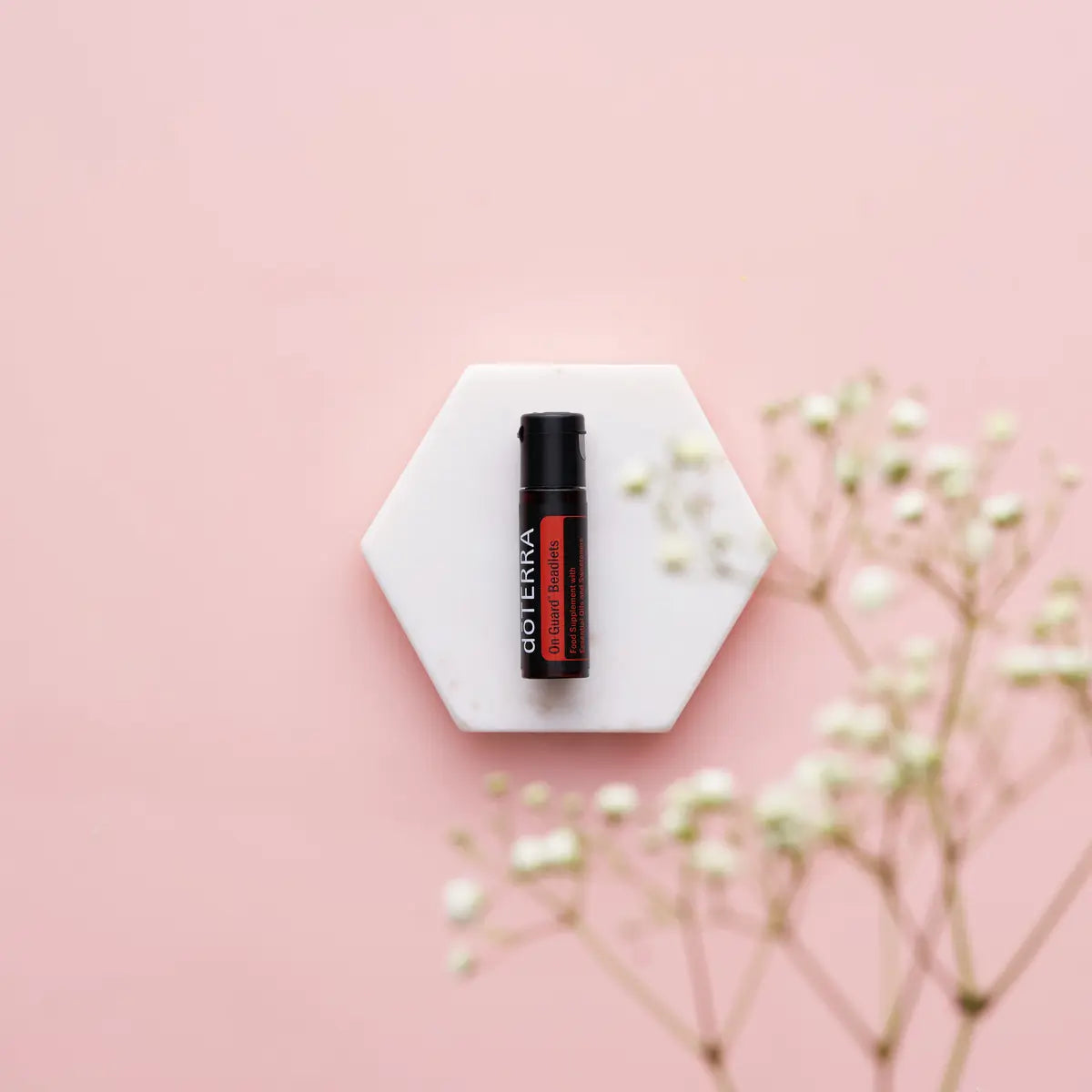 Micro-esferas On Guard doTERRA — base de mármore hexagonal com gypsophila, flores brancas e rosa, proteção natural CPTG