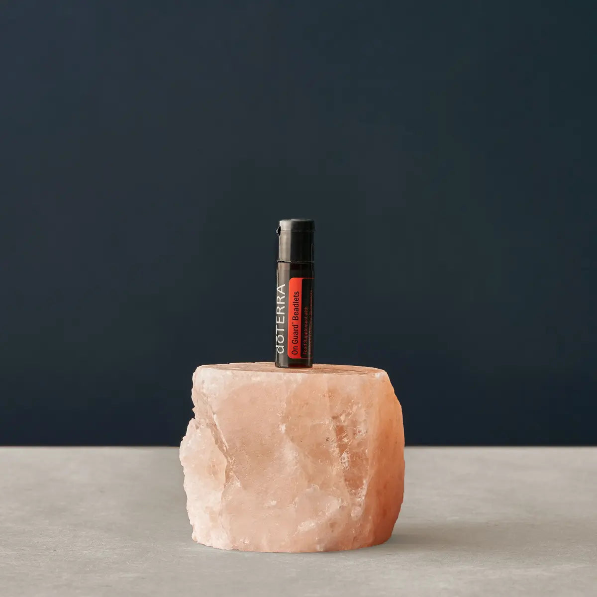 Micro-esferas On Guard doTERRA — frasco com bloco de sal himalaia, fundo azul ardósia, suplemento imunidade CPTG