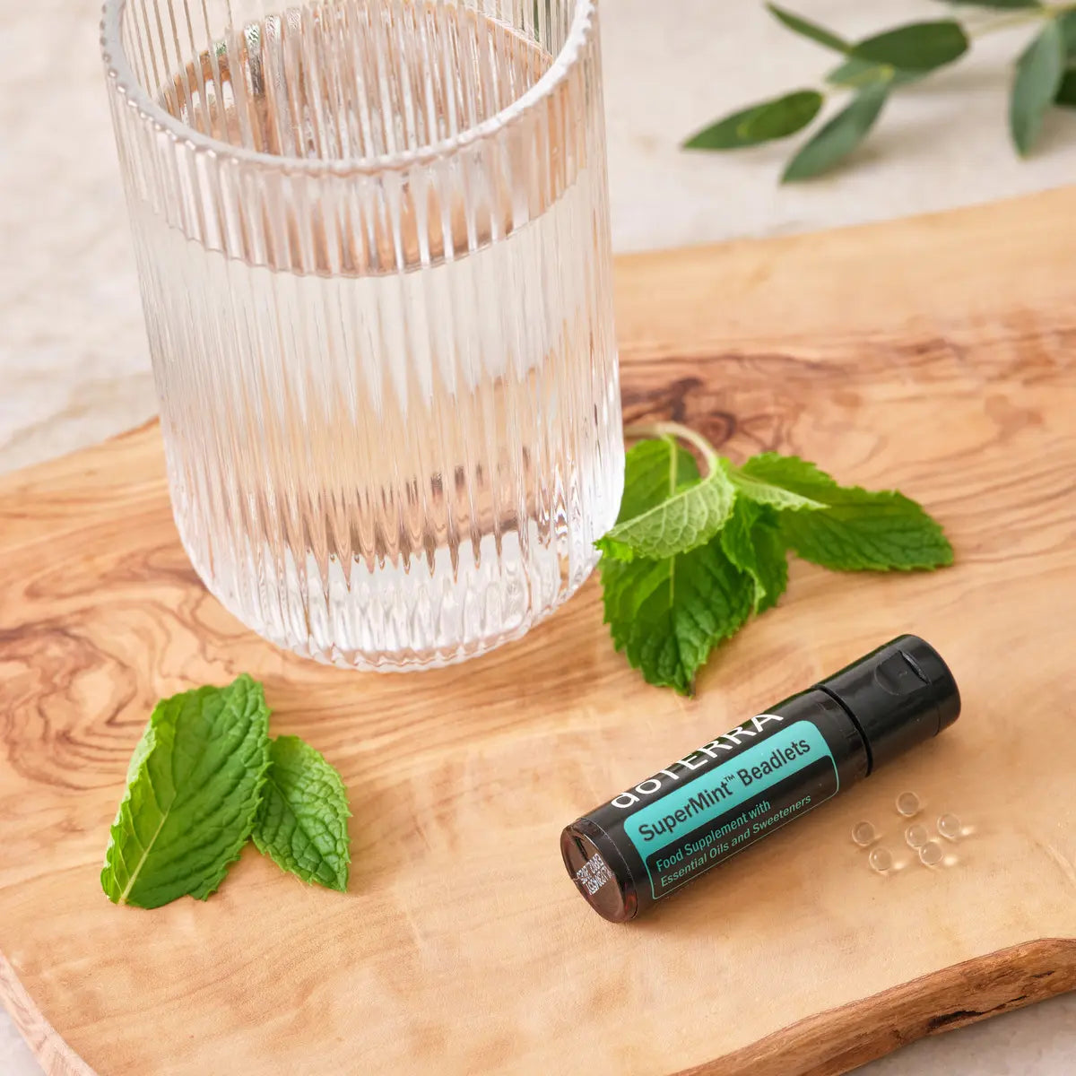 Beadlets Supermint doTERRA — frasco em tábua de oliveira com vaso de água e folhas de hortelã, menta CPTG