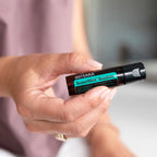 Beadlets Supermint doTERRA — mão segurando frasco horizontal, bokeh violeta, frescura natural CPTG