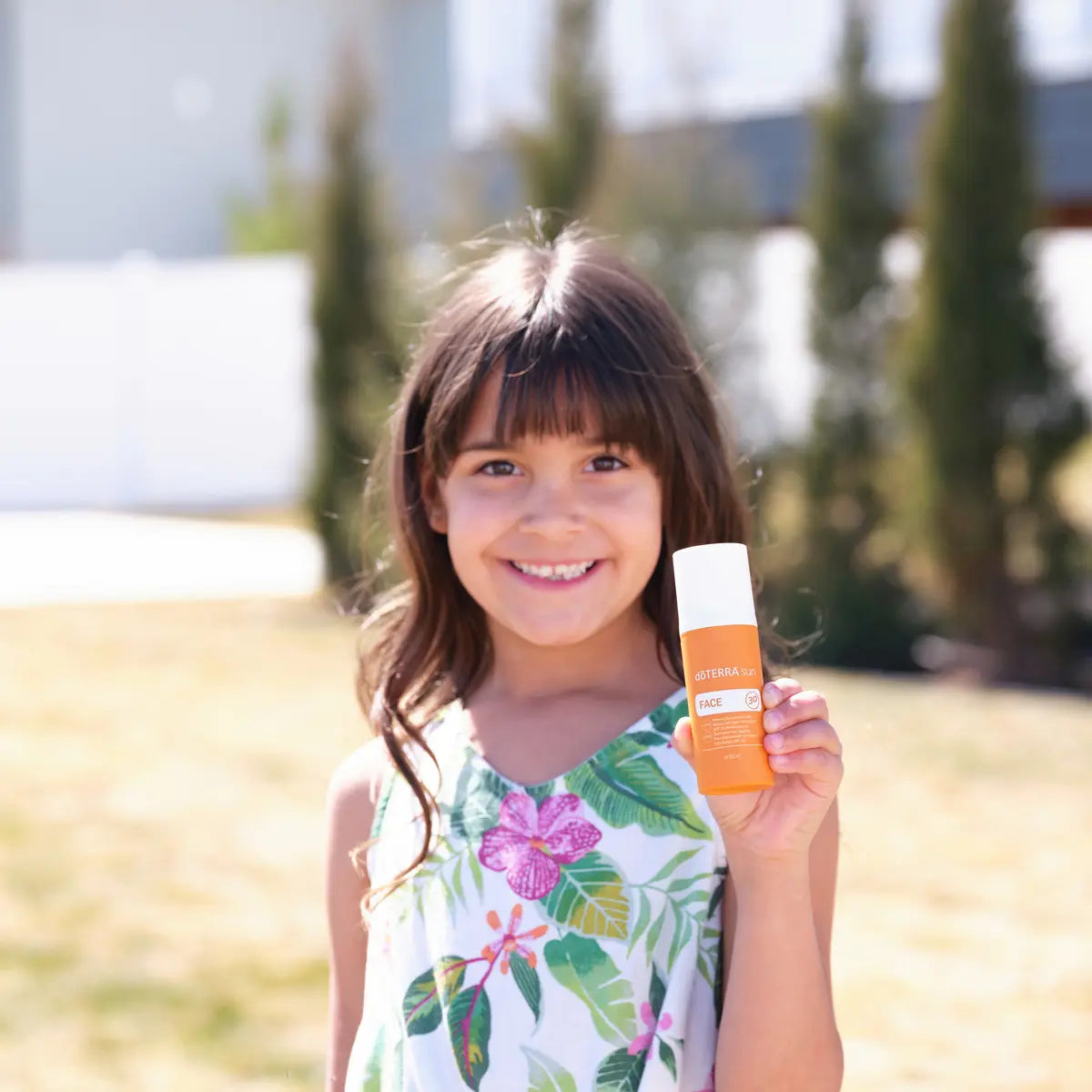 Protetor Solar Mineral Hidratante doTERRA SPF30 — menina morena sorridente no jardim, proteção solar rosto CPTG