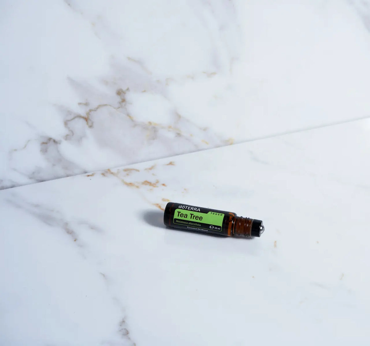 Melaleuca Touch doTERRA Roll-on 10ml — deitado em mármore branco dourado, árvore de chá puro CPTG